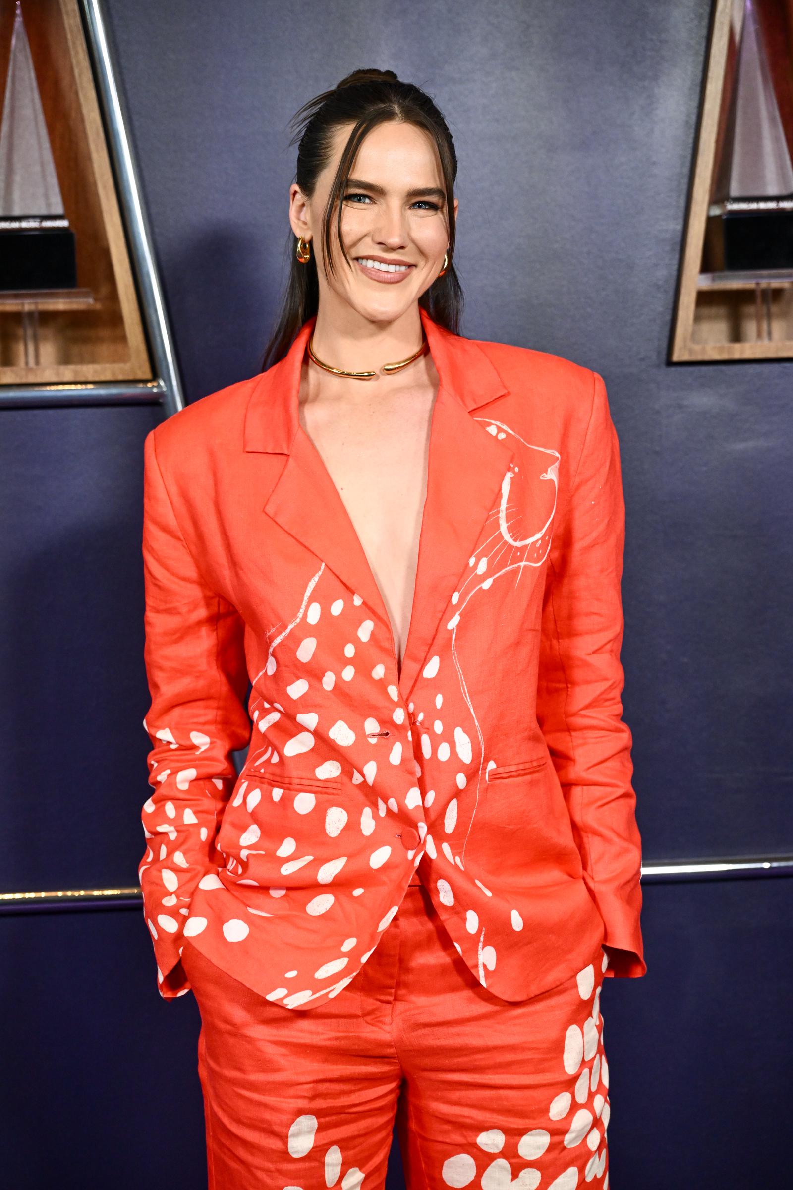 Sophie Hawley-Weld made waves at the 2025 AMAs at Fontainebleau Las Vegas on May 26, stepping out in a fiery orange suit hand-painted with white spotted motifs—a striking blend of bold color and organic, graphic detail.