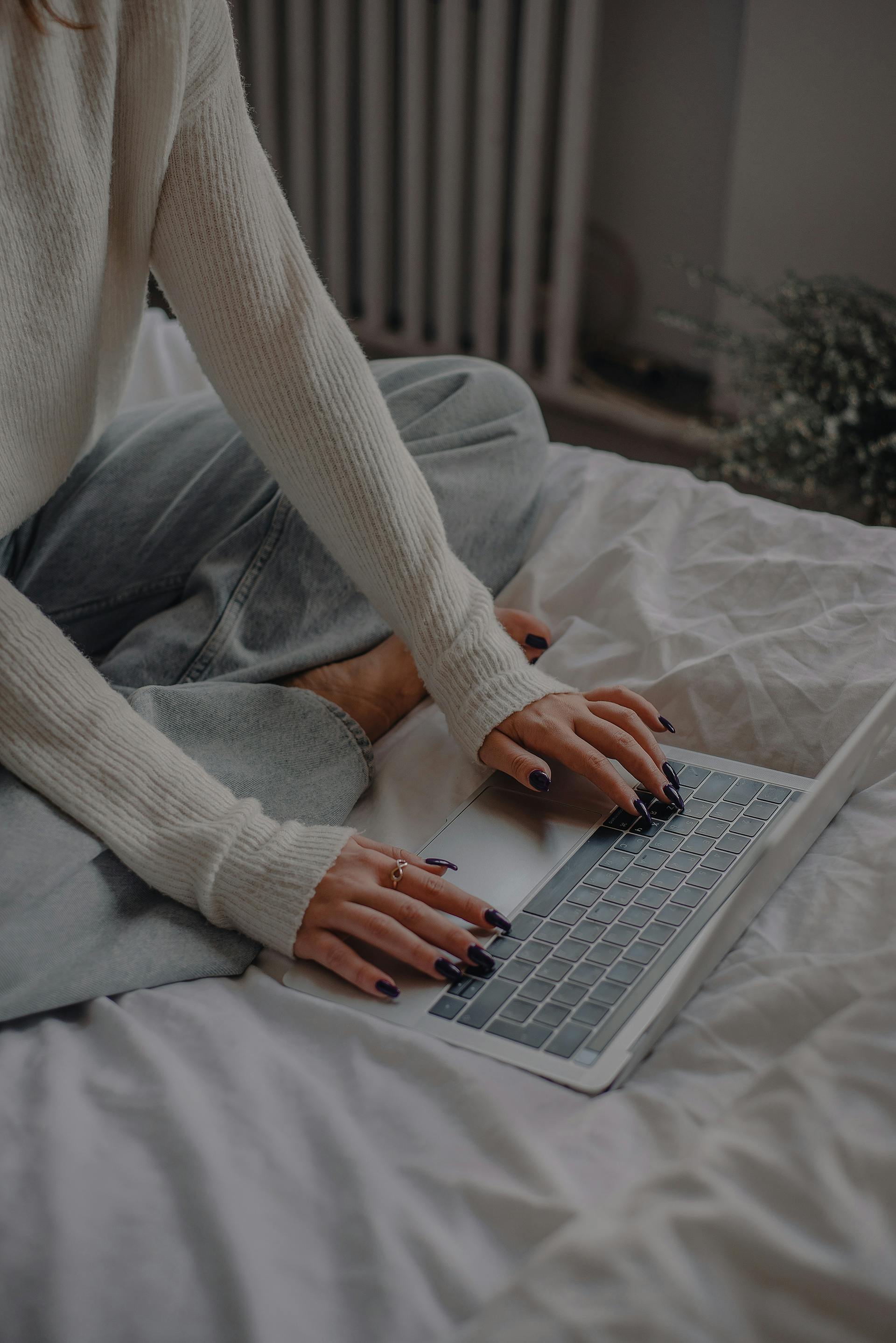 A woman sitting on the bed and using a laptop | Source: Pexels
