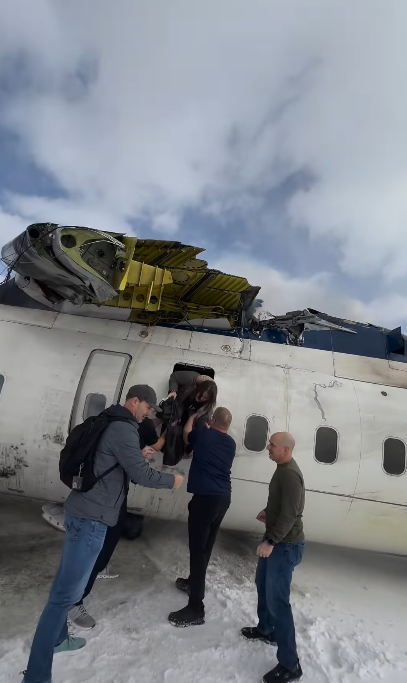A passenger climbs through an emergency exit while other individuals assist them down from the wrecked fuselage | Source: Instagram/eggxit