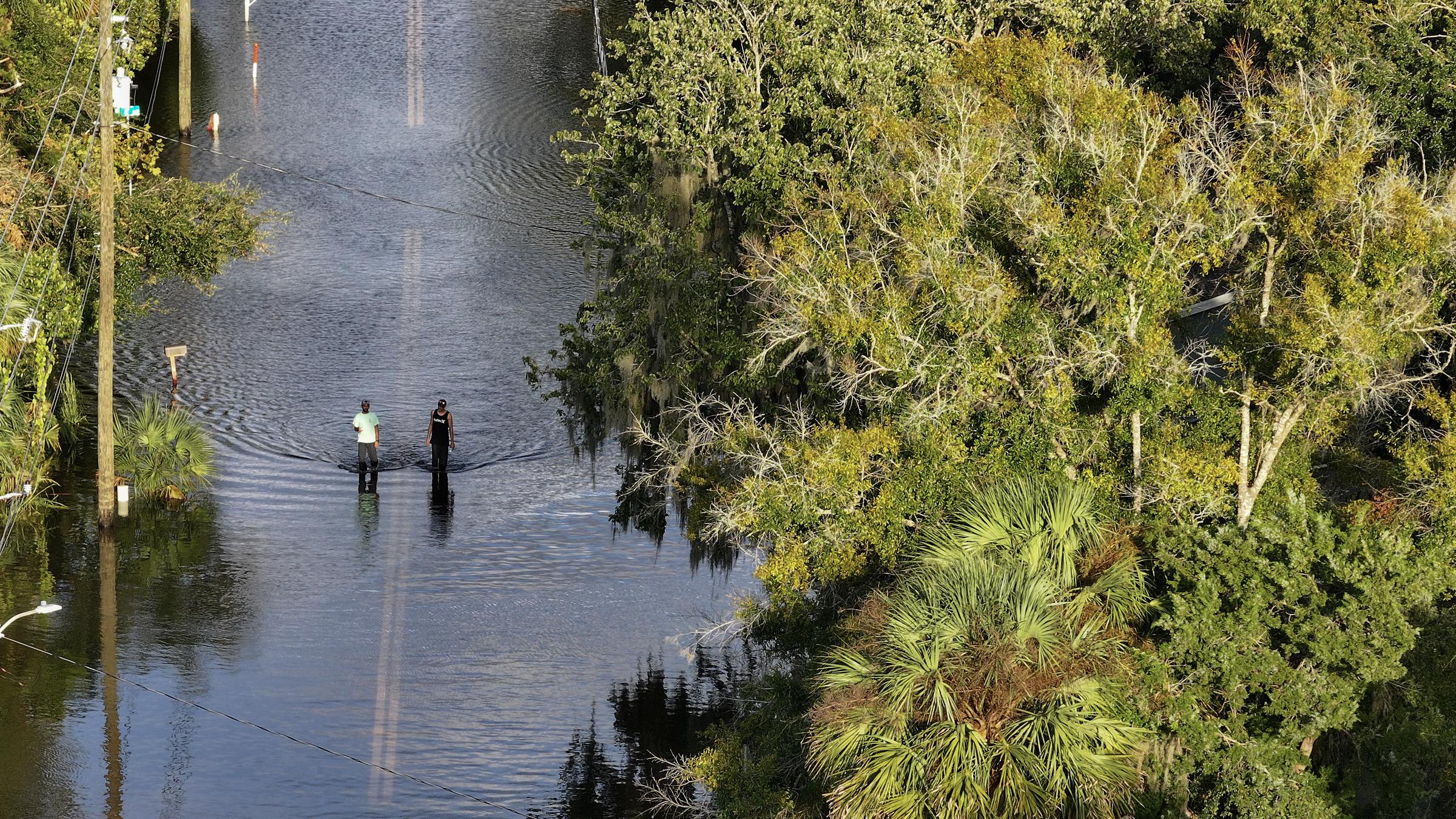 People walk through flood waters along a road after Hurricane Helene hit the area as it passed offshore in Crystal River, Florida, on September 27, 2024 | Source: Getty Images