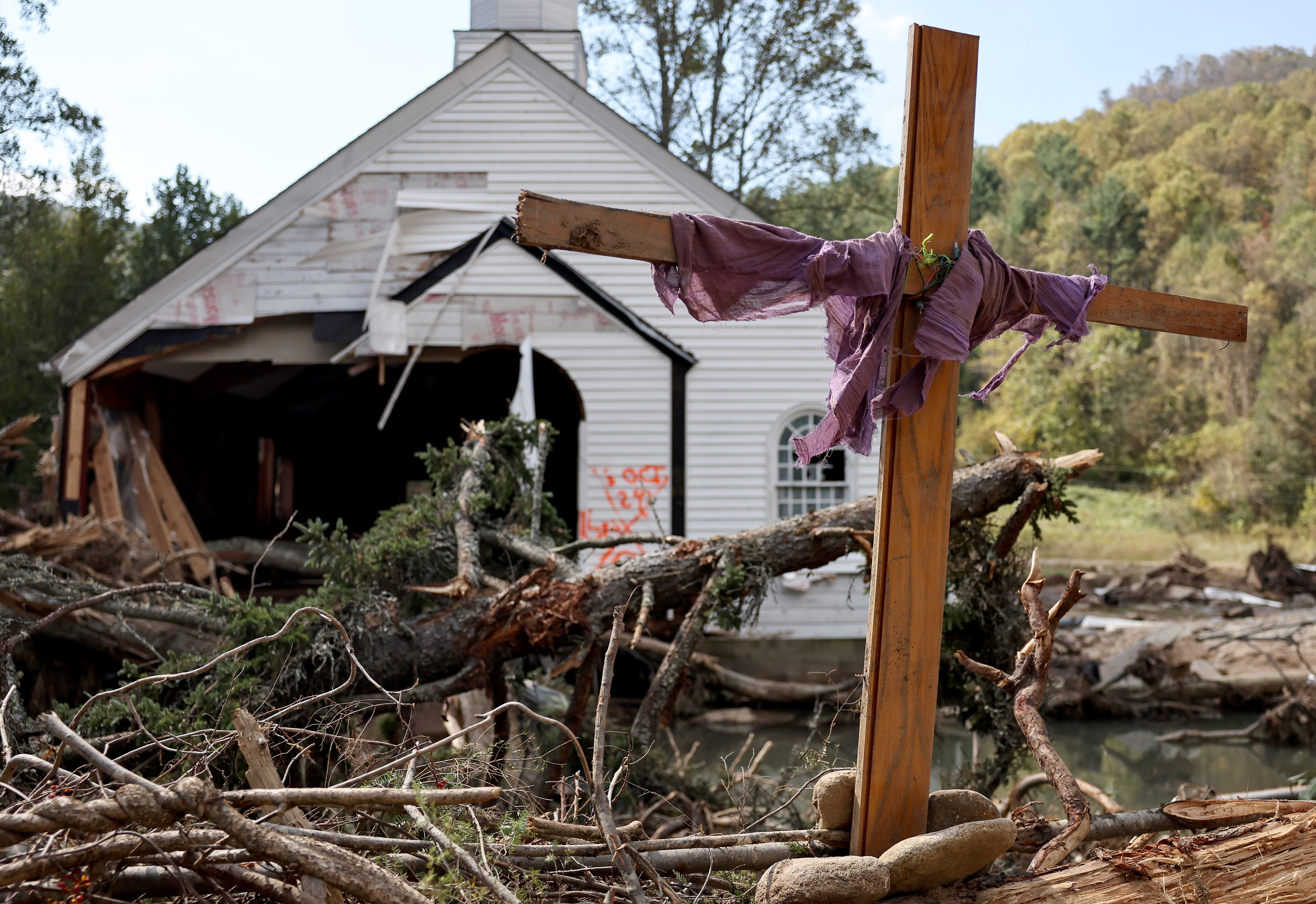 A makeshift cross stands amid fallen trees in front of a destroyed church in the aftermath of Hurricane Helene flooding in Swannanoa, North Carolina, on October 6, 2024 | Source: Getty Images