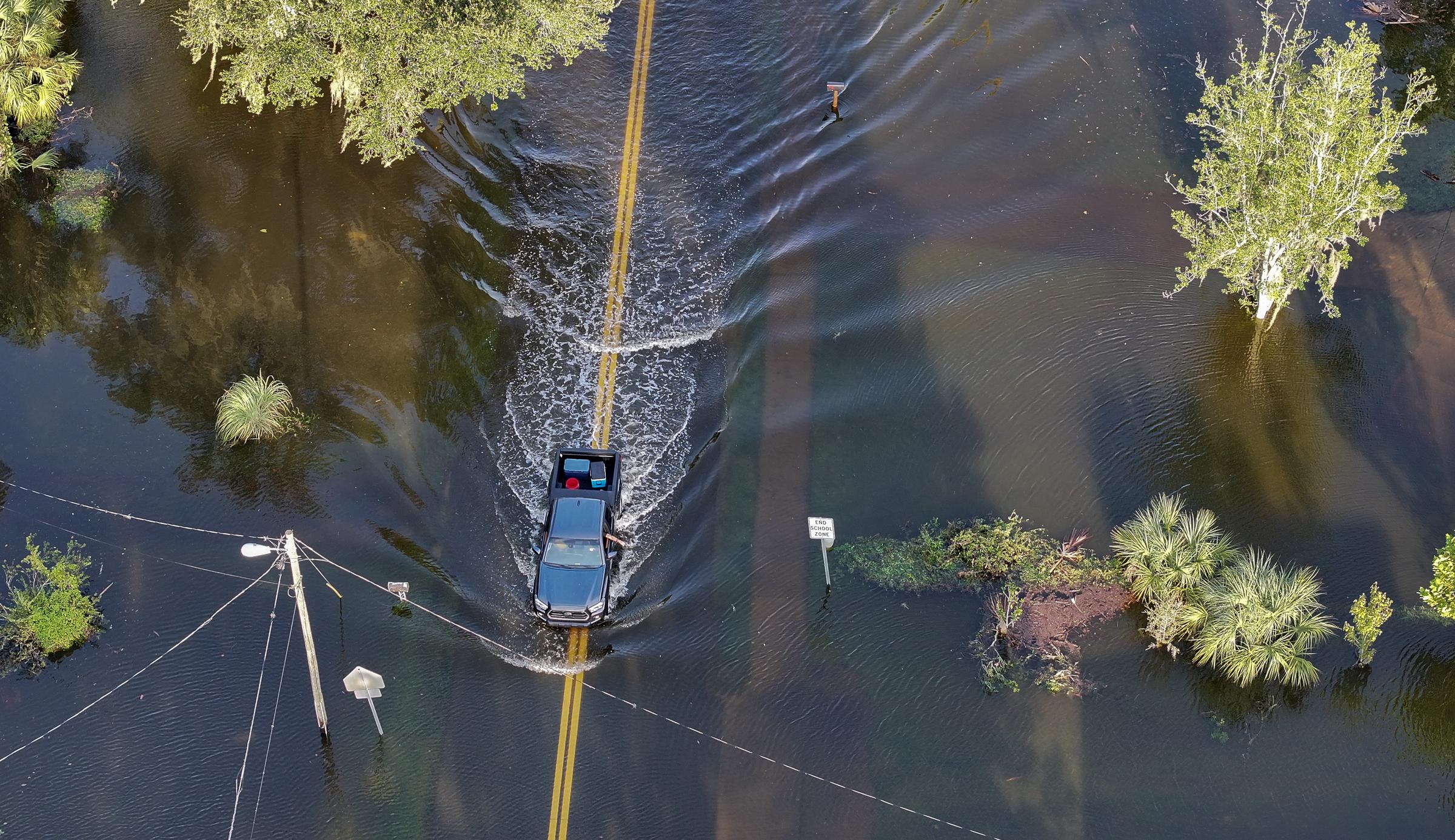 A vehicle drives through flood waters after Hurricane Helene hit the area as it passed offshore in Crystal River, Florida, on September 27, 2024 | Source: Getty Images